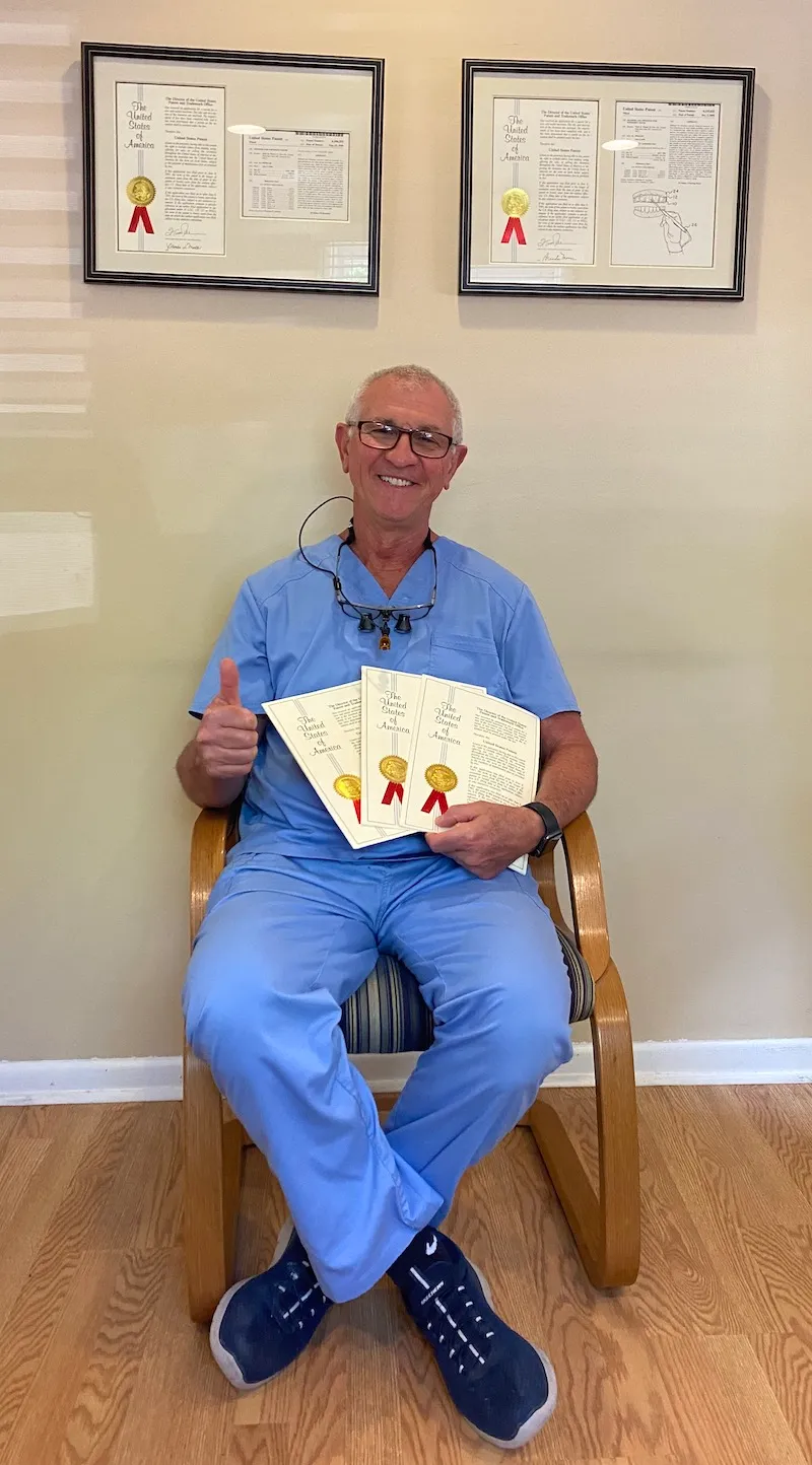 Dr. Wisel smiling wearing scrubs while holding his patents